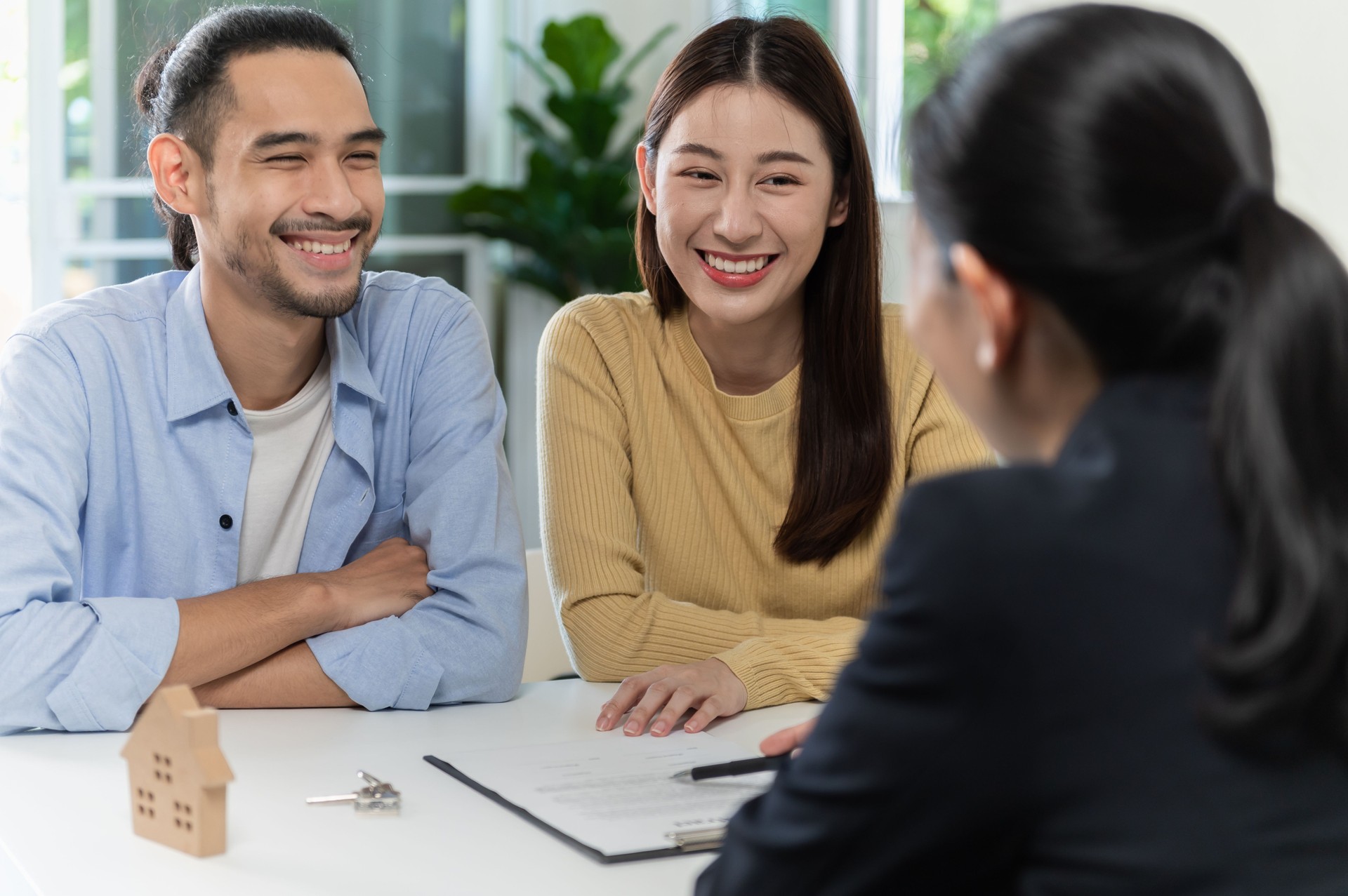 Real estate sales agent explain rental or buying condition to young couple before move to new home or apartment at real estate sales office. Asian urban lifestyle or real estate business concept.